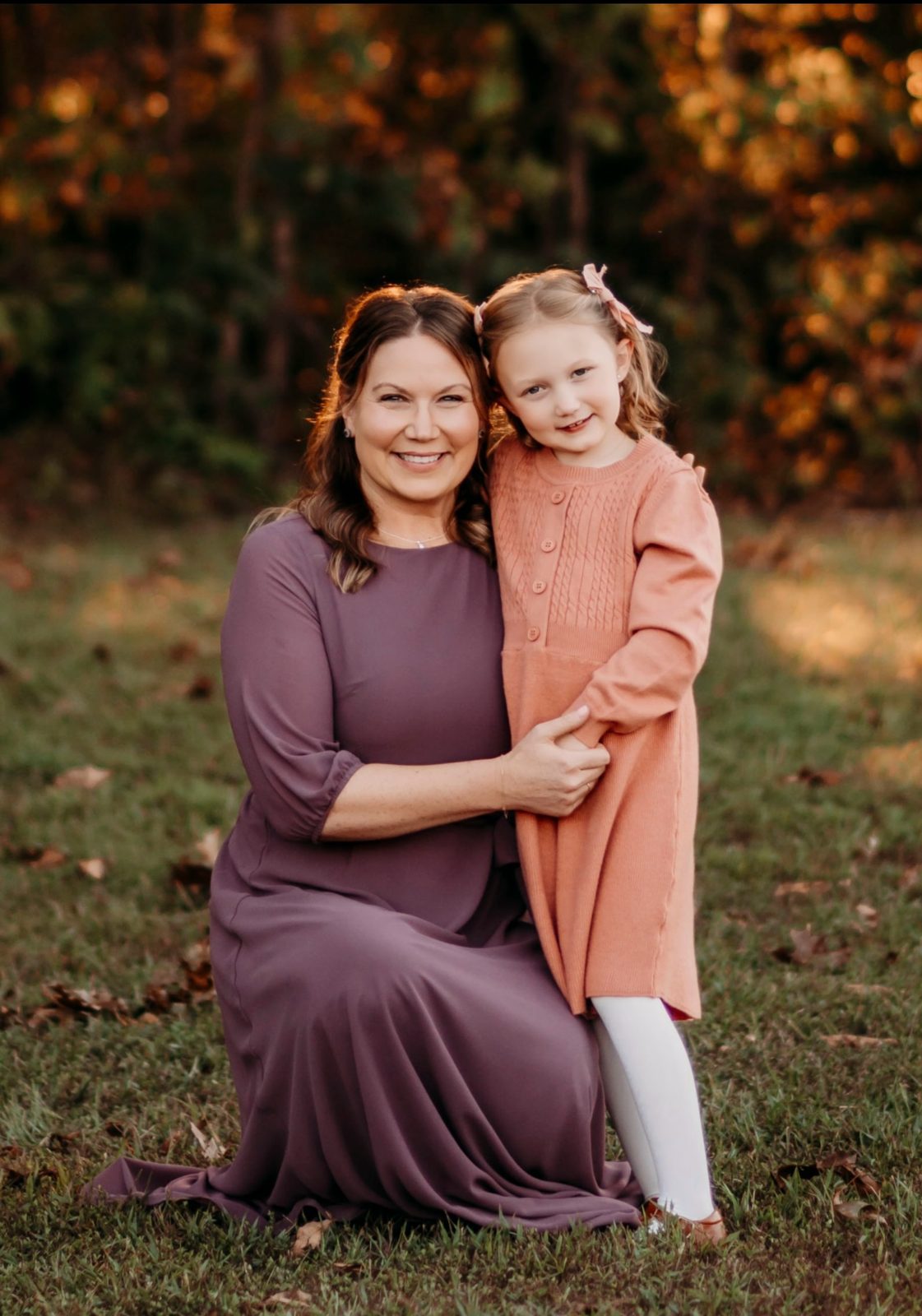 Jennifer kneeling beside Emma outdoors in autumn